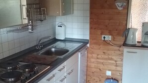 Una cocina con estufa, fregadero, armarios y un reloj en la pared.