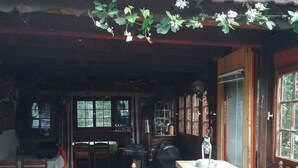 Un espacio al aire libre con sillas y mesas de madera, una parrilla y un porche cubierto.