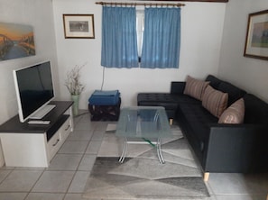 A living room with a TV, sofa, and a glass coffee table.