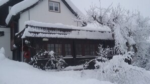 Un edificio imbiancato dalla neve con un design tradizionale, caratterizzato da un tetto a falde e una finestra ben visibile.