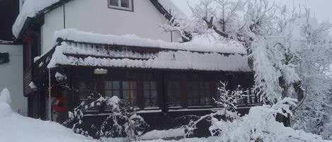 Un bâtiment recouvert de neige, de conception traditionnelle, avec un toit en pente et une fenêtre bien visible.
