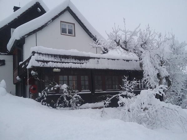 A snow-covered building with a traditional design, including a pitched roof and a visible window.