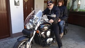 Una motocicletta parcheggiata di fronte a un edificio con una porta di legno e una decorazione a forma di cuore.