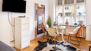 Un salon moderne avec un téléviseur à écran plat, des meubles blancs, une table en verre et un tapis en peau de vache.