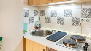 Une cuisine équipée d’un évier, d’une cuisinière et d’un plan de travail carrelé.