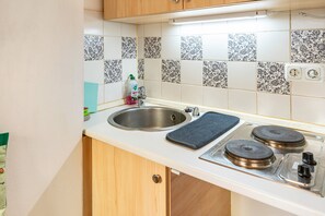 A kitchen with a sink, stove, and tiled backsplash.