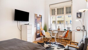 Une chambre d’hôtel moderne équipée d’un lit, d’un bureau, d’une chaise, d’une télévision et d’une grande fenêtre.