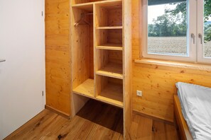 A room with a wooden wardrobe, a bed, and a window with a view of trees. - Holiday Home "Ferienhaus Das Kleine Paradies" with Sauna, Garden and Wi-Fi (Liebenau)