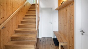 A wooden staircase leading to a white door, with a bench and coat hooks on the right.