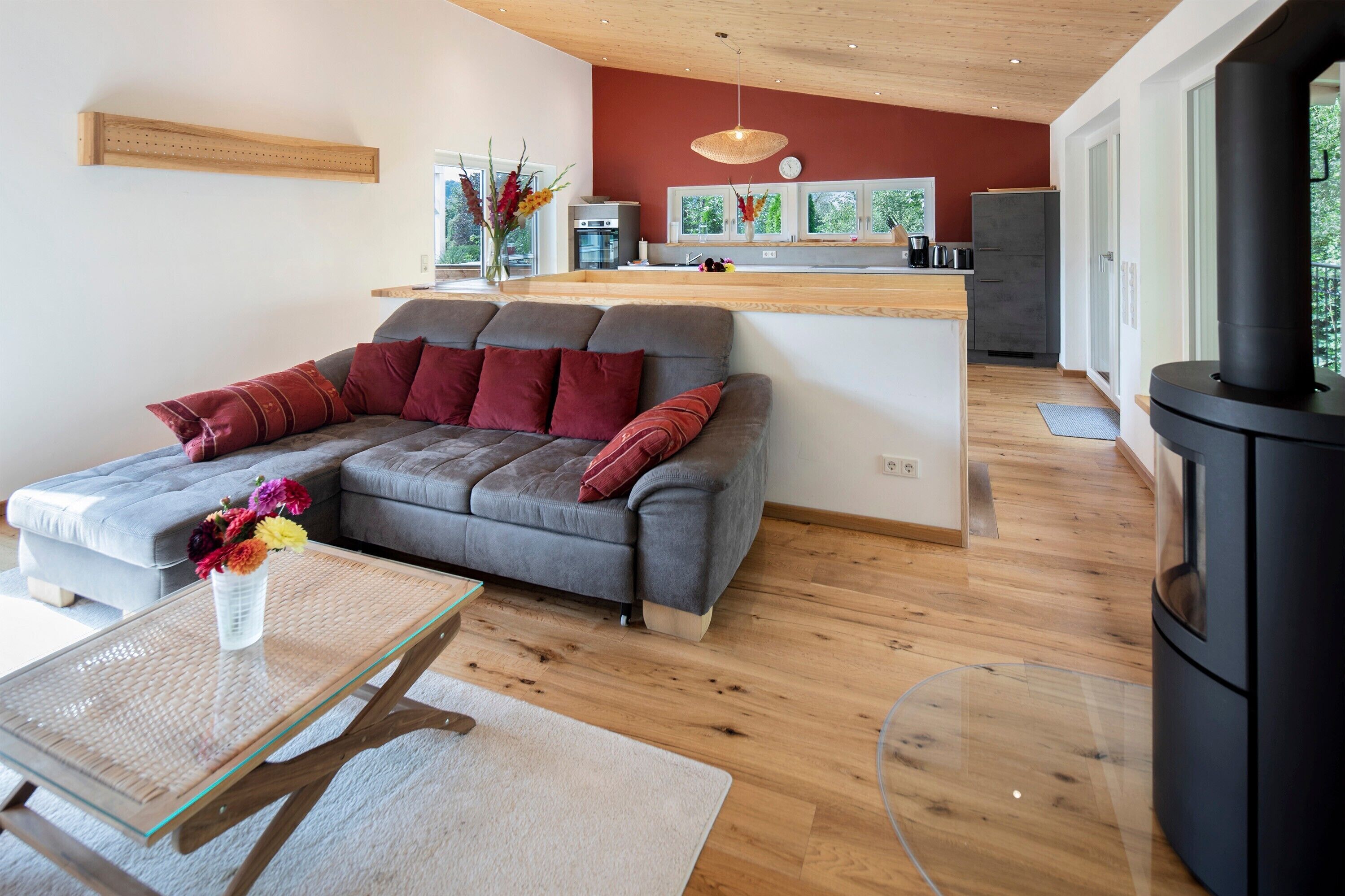A modern living room with a grey sofa, a glass coffee table, and a black wood-burning stove.