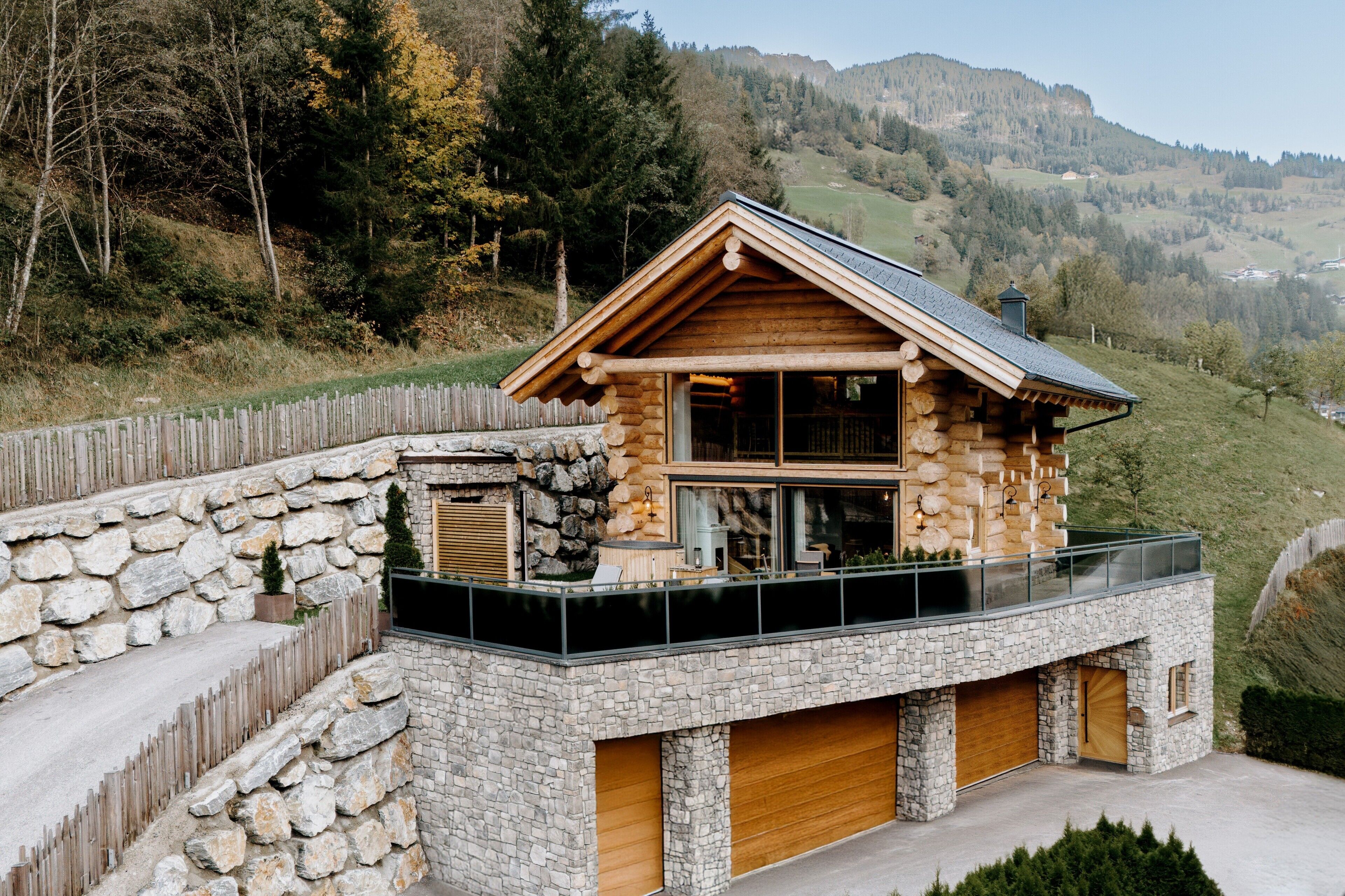 Eine Blockhütte mit Steinverkleidung, einem Balkon und einer Garage.