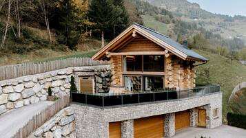 Eine Blockhütte mit Steinverkleidung, einem Balkon und einer Garage.