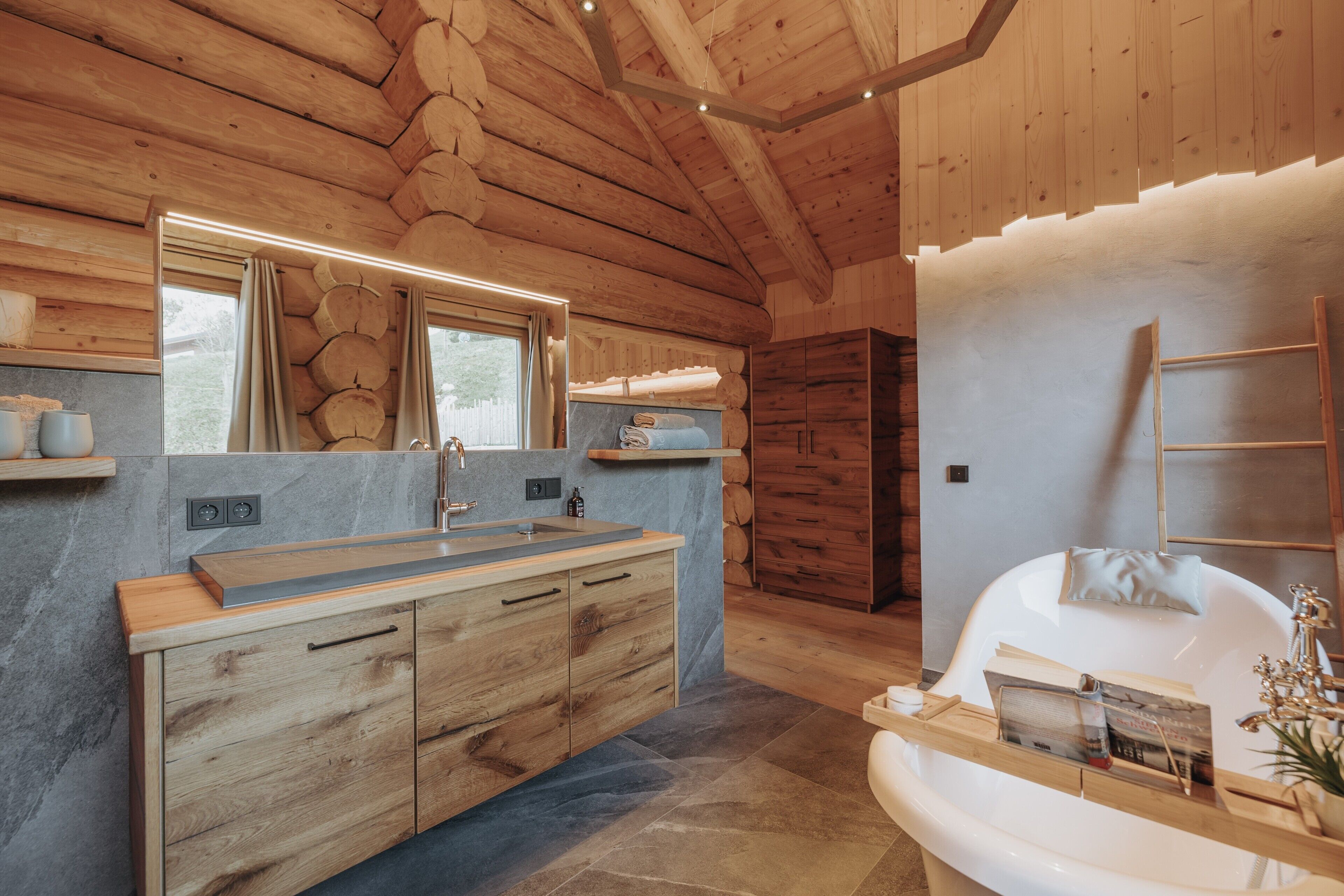 A modern bathroom with a wooden ceiling, a large mirror, a sink, and a bathtub.