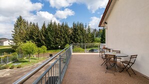 A balcony with a table and chairs, a railing, and a view of trees and houses. - Apartment 'Friedmann' with Private Garden, Balcony and Wi-Fi (Offingen)