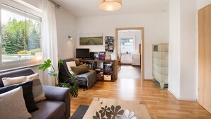 A modern living room with a sofa, a coffee table, a TV, and a bookshelf. - Apartment 'Friedmann' with Private Garden, Balcony and Wi-Fi (Offingen)