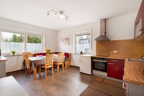 A compact kitchen with a dining area, a built-in oven, and a small refrigerator.