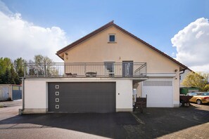 A two-story building with a garage, a balcony, and a small window.