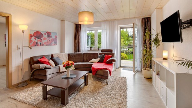 Ein modernes Wohnzimmer mit einer Couch, einem Couchtisch und einem Flachbildfernseher.