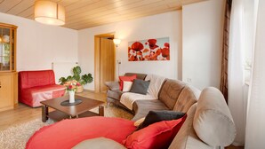 Ein Wohnzimmer mit einem roten Sofa, einem beigen Sofa, einem Holztisch und einem Gemälde an der Wand.