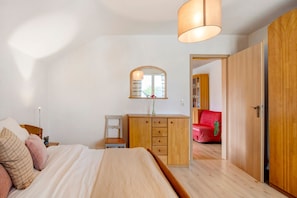 A bedroom with a bed, wooden wardrobe, and a mirror.