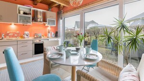 Une cuisine moderne avec un coin repas, de grandes fenêtres et une vue sur l’extérieur.