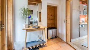 Une cuisine compacte dotée d’un plan de travail en bois, d’une poubelle et d’une petite étagère sur laquelle est posé un objet décoratif.