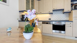 Una cocina moderna con armarios de madera, horno integrado y una orquídea en maceta sobre la encimera.
