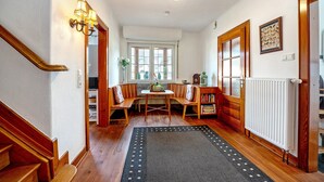 A hallway with a wooden staircase, a bench seating area, a table with chairs, a radiator, and a window. - Holiday Home 'Domäne Bollinger Morbach' with Private Terrace, Private Garden and Wi-Fi (Morbach)