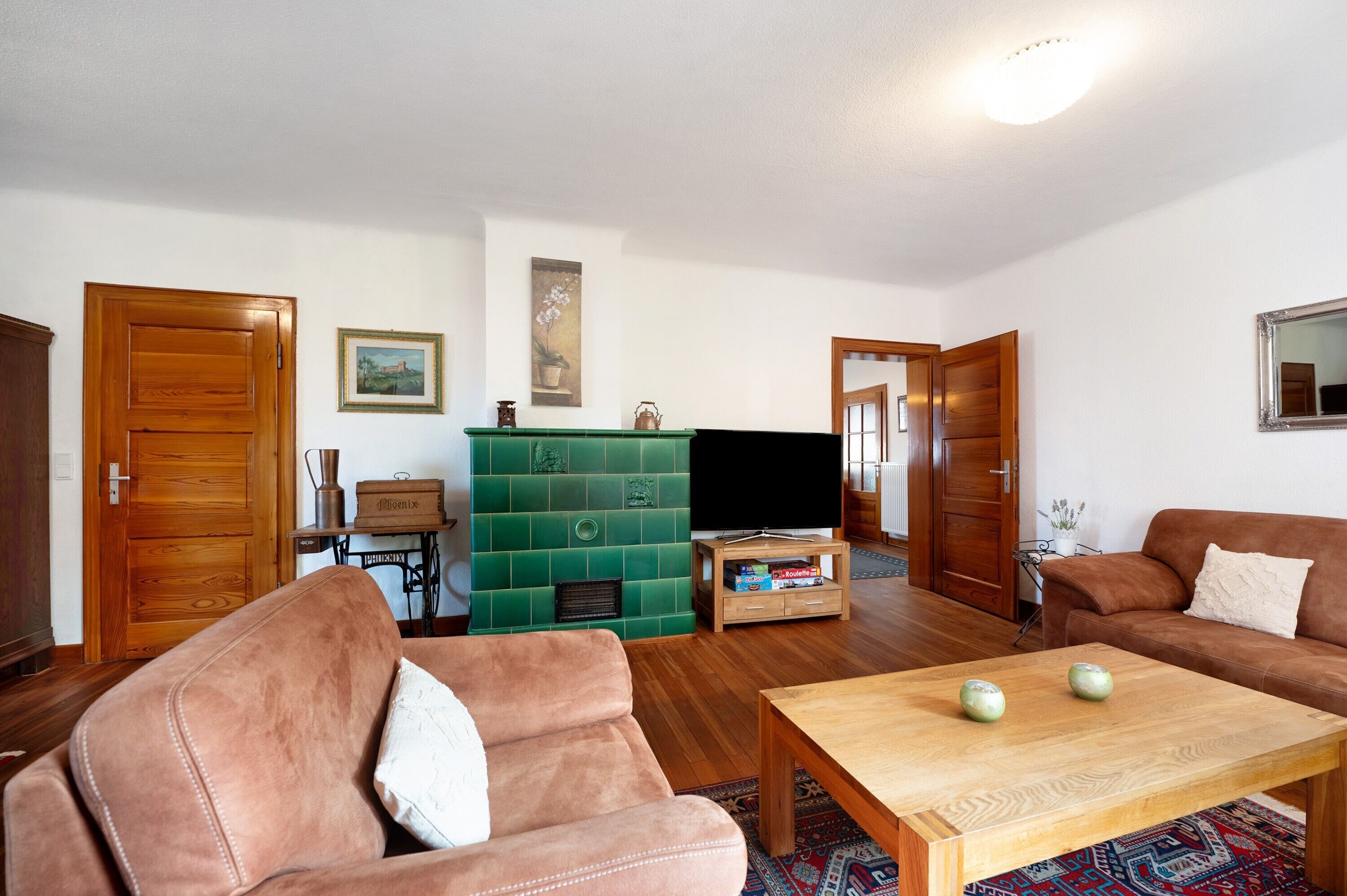 A living room with a sofa, a coffee table, a television, and a green cabinet.