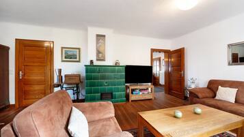 A living room with a sofa, a coffee table, a television, and a green cabinet.