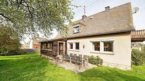 A house with a sloped roof, a satellite dish, and a small porch with outdoor seating. - Holiday Home 'Domäne Bollinger Morbach' with Private Terrace, Private Garden and Wi-Fi (Morbach)