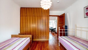 A bedroom with two single beds, wooden wardrobe, white ceiling, and a hanging light fixture. - Holiday Home 'Domäne Bollinger Morbach' with Private Terrace, Private Garden and Wi-Fi (Morbach)