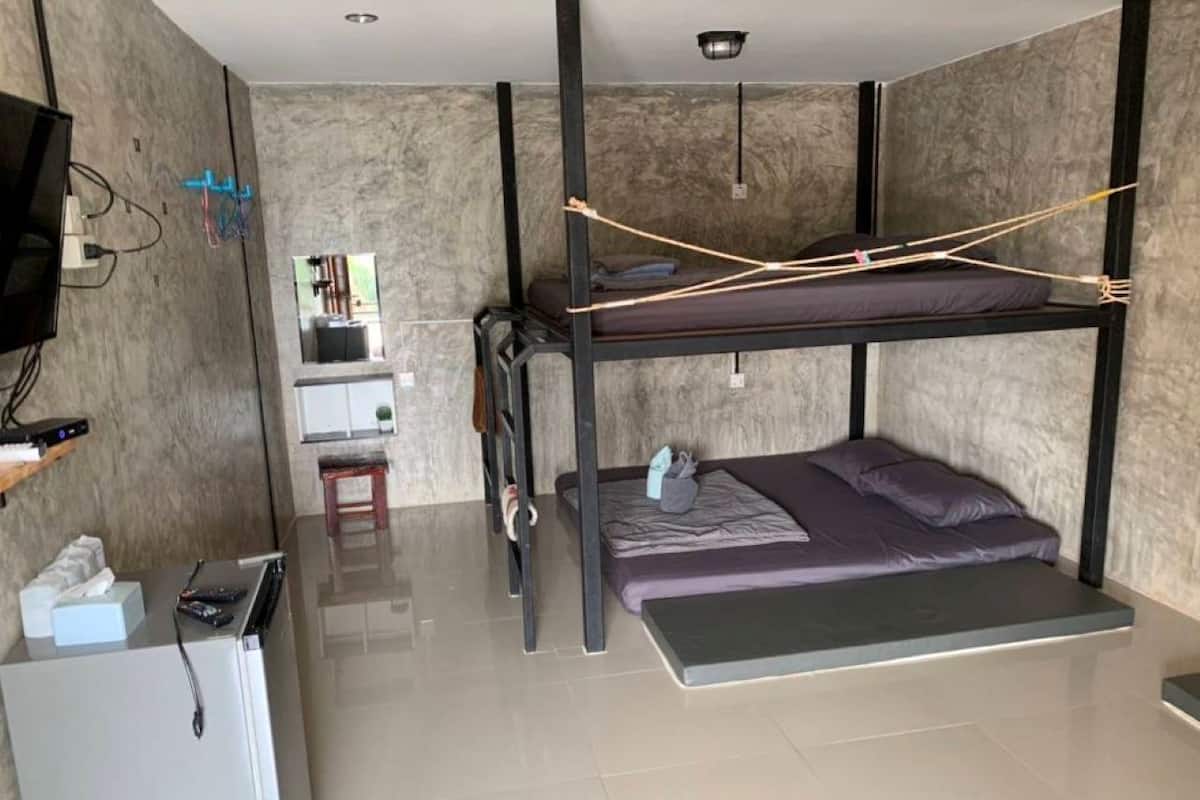 A bunk bed room with a small kitchenette area, a TV, and a mirror.