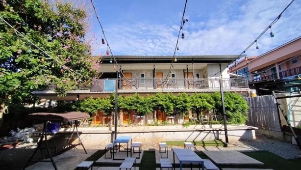 An outdoor patio area with tables and chairs, a covered seating area, and a building in the background. - Rakchayanin Resort Koh Larn (Koh Lan)