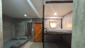 A dormitory room with bunk beds, a wooden door, and a curtain. - Rakchayanin Resort Koh Larn (Koh Lan)