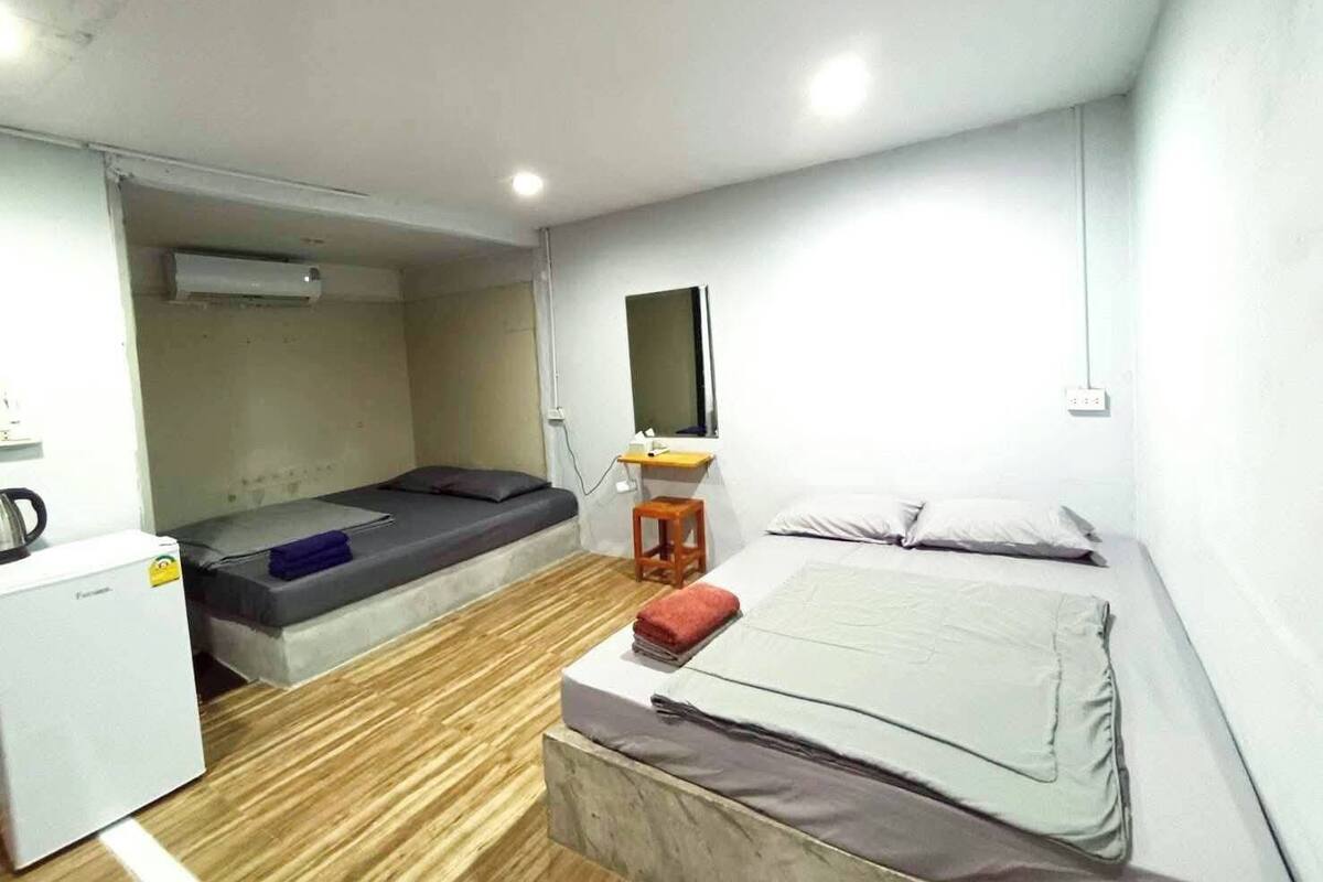 A compact room with a bed, a desk, a chair, and a small kitchenette.