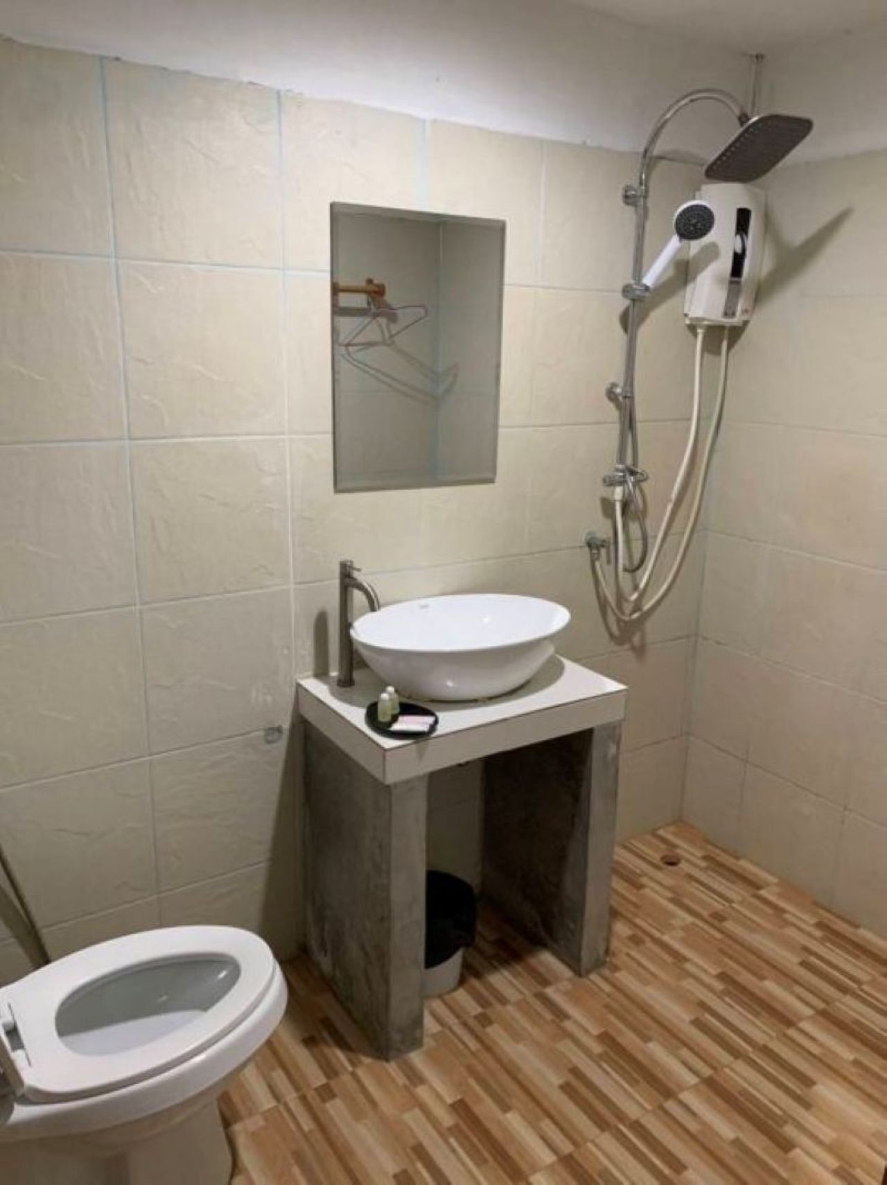 A bathroom with a toilet, a pedestal sink, a shower, and a mirror.