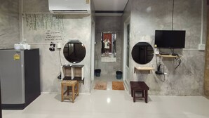 A modern, minimalist room with a large mirror, a flat-screen TV, and a built-in air conditioning unit. - Rakchayanin Resort Koh Larn (Koh Lan)