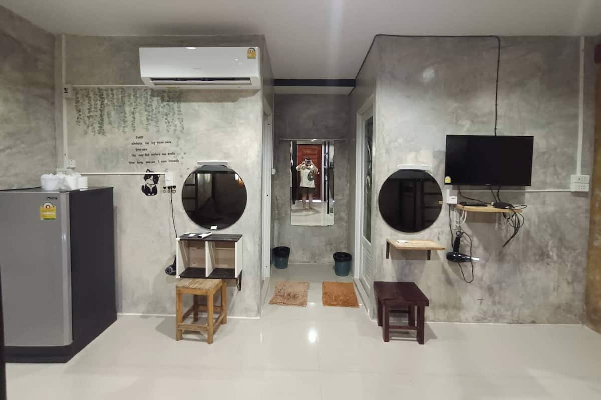 A modern, minimalist room with a large mirror, a flat-screen TV, and a built-in air conditioning unit.