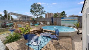 Un patio trasero con piscina, sillas de deck y valla de madera.