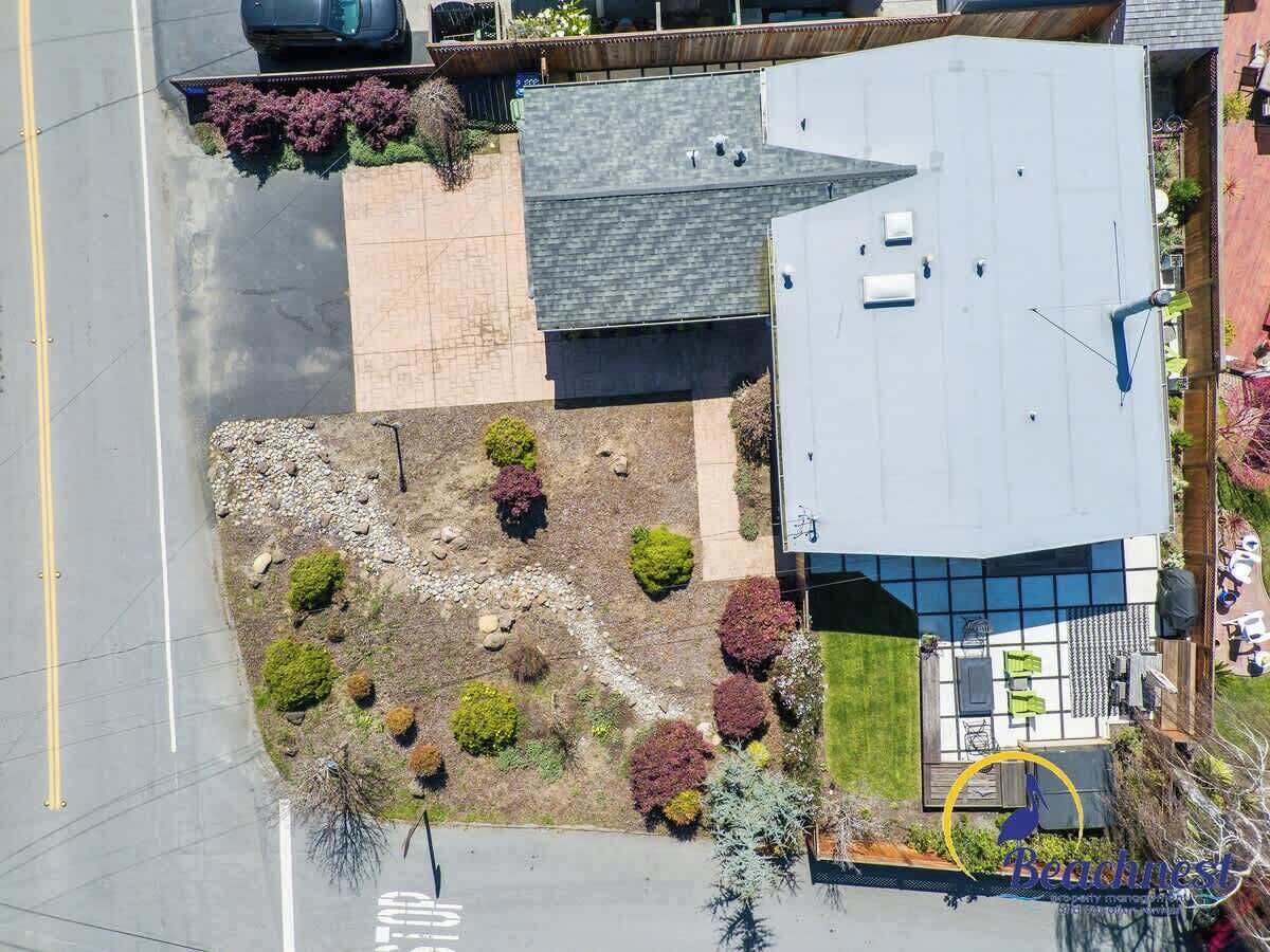 Vue aérienne d’une propriété résidentielle dotée d’un jardin aménagé, d’un patio couvert et d’un garage.
