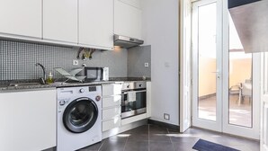 Una cocina moderna con lavadora, microondas, horno y salpicadero de azulejos.
