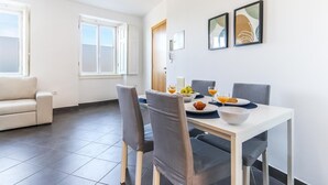 Un comedor moderno con una mesa blanca, sillas grises y un sofá blanco al fondo.