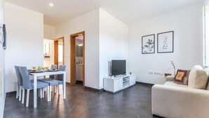 Una sala de estar moderna con comedor, televisor y sofá.