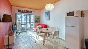 A compact living space with a kitchenette, a dining area, and a sofa.