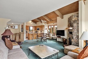 A spacious living area with a dining table, sofas, and a kitchen in the background.