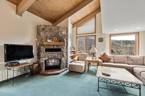 A living room with a stone fireplace, a flat-screen TV, a sofa, and a coffee table.