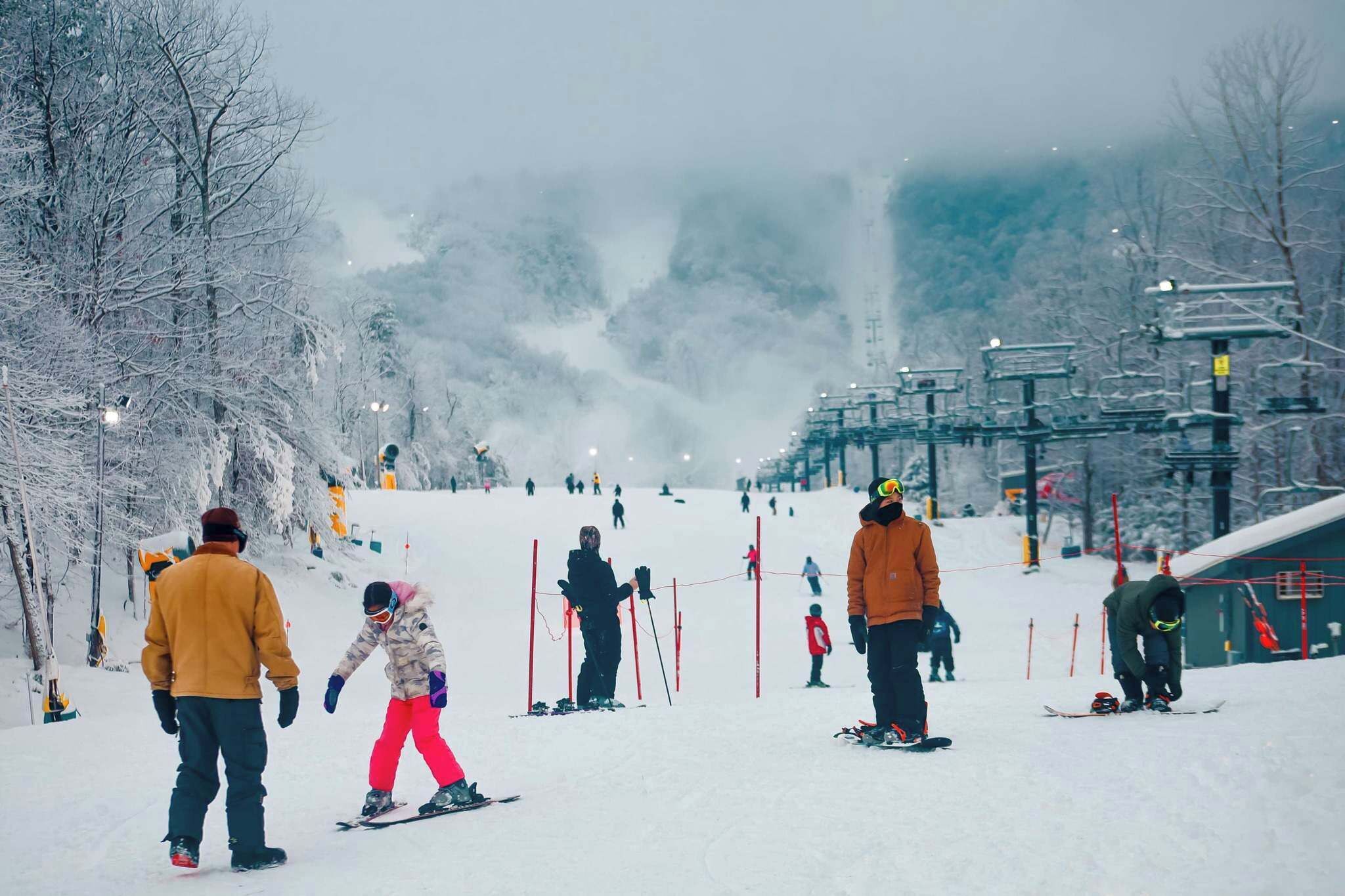 A snowy ski slope with skiers and snowboarders.