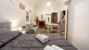 A compact hotel room with a bed, a sofa, a small dining table, and a kitchen area. - GuestHost - Casa Vita 51 in Ceglie Messapica (Ceglie Messapica)