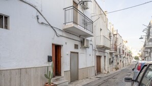A narrow street lined with white buildings, each with a wooden door and a small balcony. - GuestHost - Casa Vita 51 in Ceglie Messapica (Ceglie Messapica)